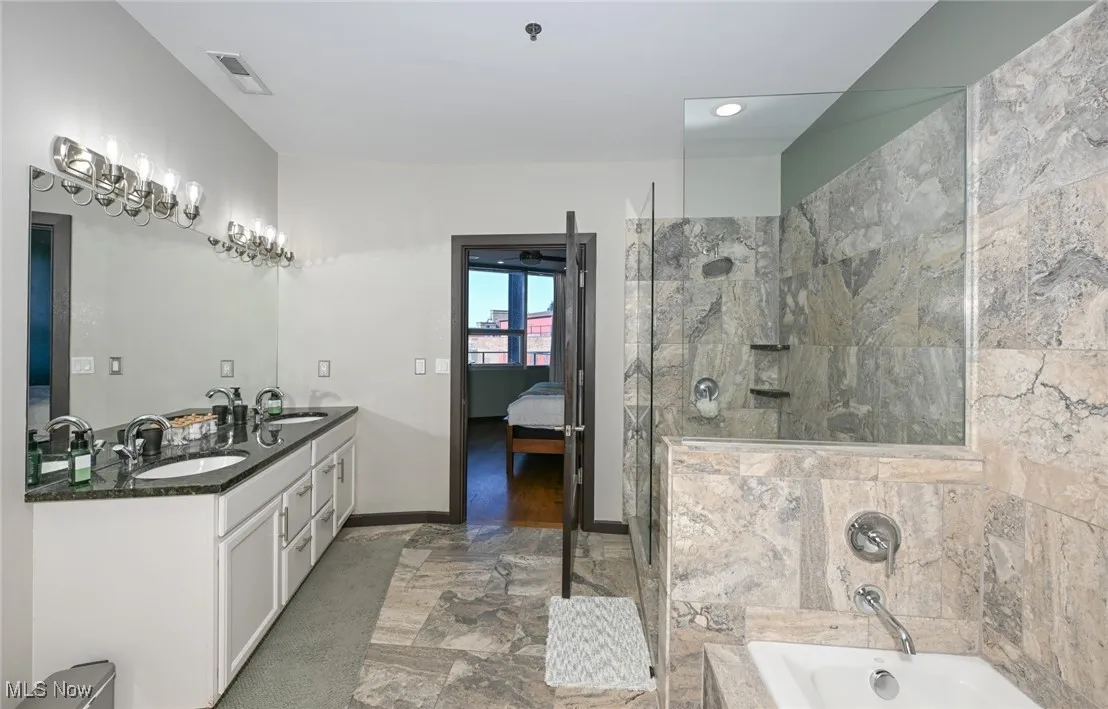 Ensuite bathroom featuring a bath, visible vents, a tile shower, a sink, and ensuite bath