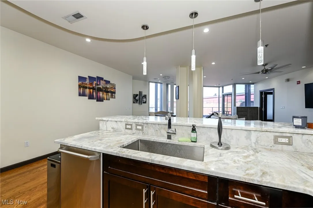 Kitchen with visible vents, dishwasher, wood finished floors, a sink, and open floor plan
