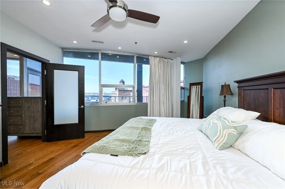 Bedroom with a city view, recessed lighting, visible vents, and wood finished floors