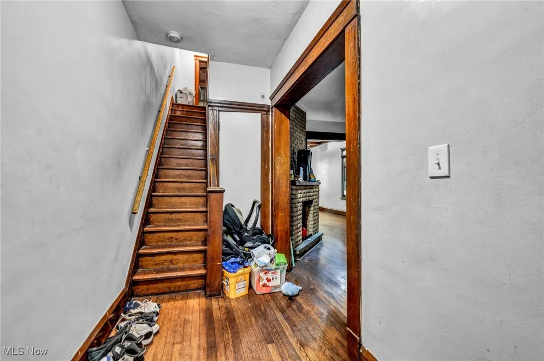 Stairs with a fireplace with raised hearth and hardwood / wood-style floors