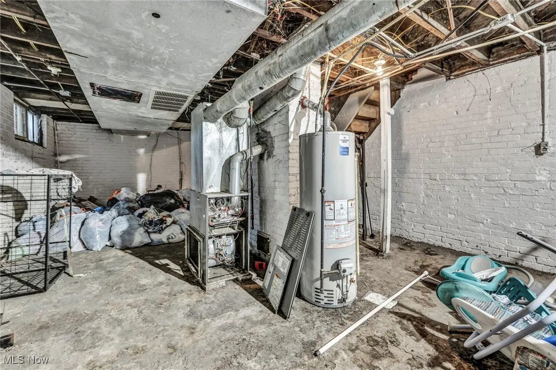 Below grade area with visible vents, gas water heater, and brick wall