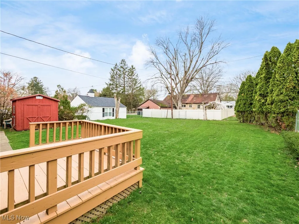 View of yard with an outdoor structure, a deck, fence, and a storage shed