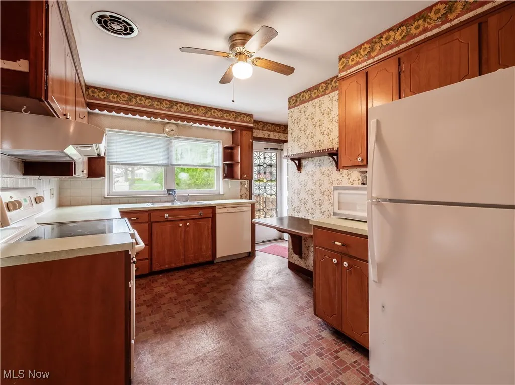 Kitchen with visible vents, white appliances, wallpapered walls, a ceiling fan, and under cabinet range hood
