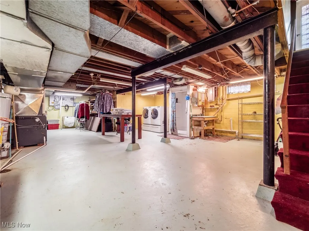 Below grade area with heating unit, stairway, and washer and dryer