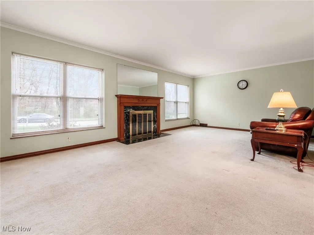 Living area with a high end fireplace, carpet, baseboards, and crown molding