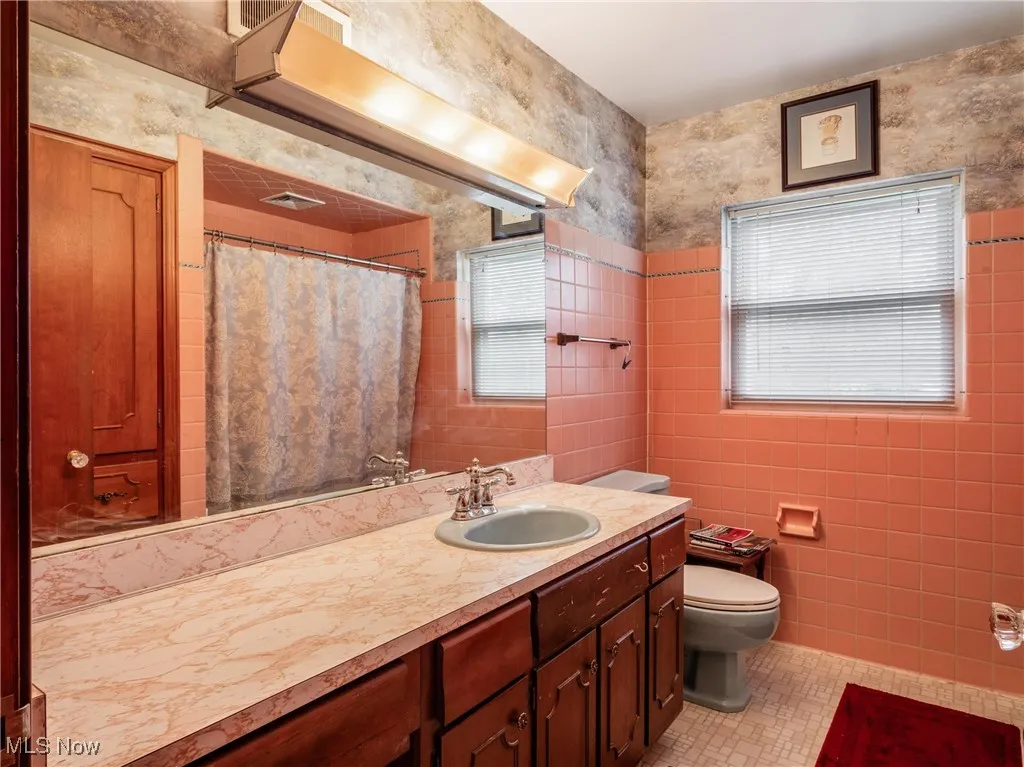 Bathroom featuring a shower with curtain, vanity, tile walls, toilet, and tile patterned floors