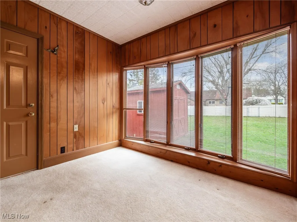 Carpeted spare room with wood walls