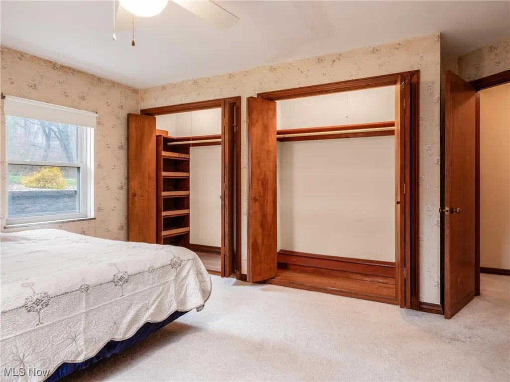 Bedroom featuring two closets, wallpapered walls, carpet floors, and baseboards