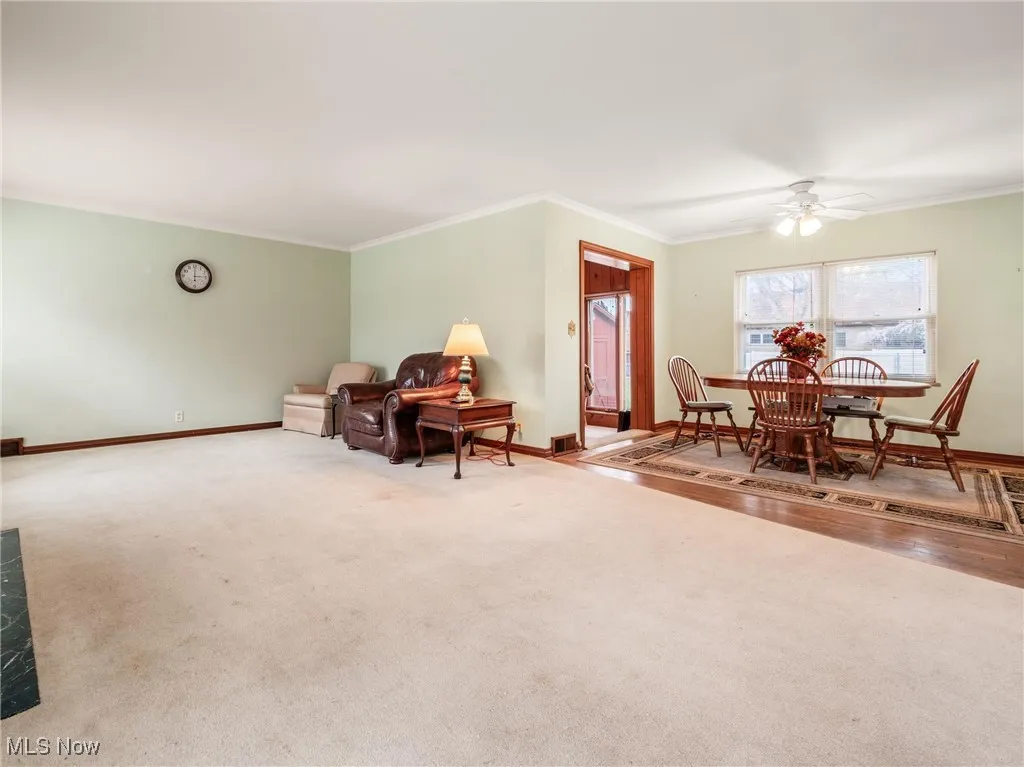 Carpeted living area with crown molding, baseboards, and ceiling​​‌​​​​‌​​‌‌​‌‌​​​‌‌​‌​‌​‌​​​‌​​ fan