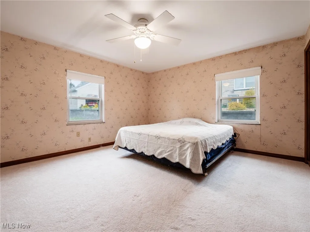 Carpeted bedroom with baseboards, ceiling fan, and wallpapered walls