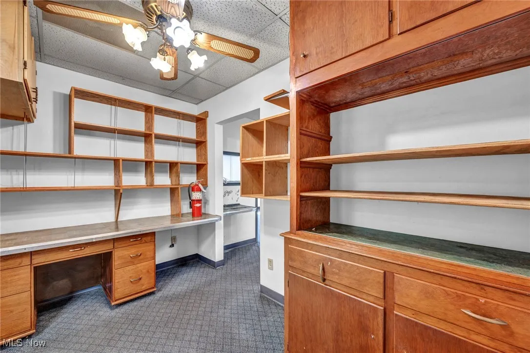 Home office with baseboards, built in study area, ceiling fan, and a paneled ceiling