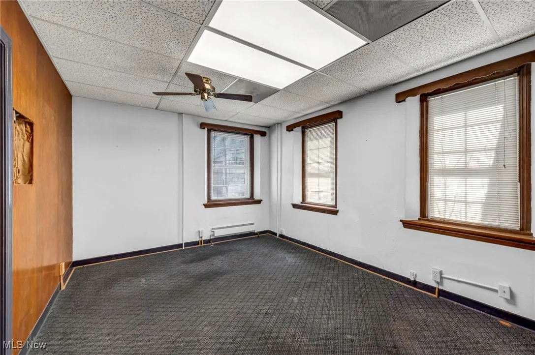 Unfurnished room with baseboards, ceiling fan, a paneled ceiling, and baseboard heating