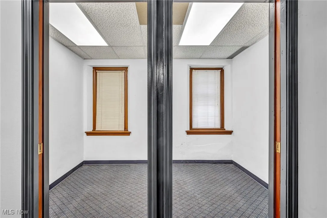 Corridor with baseboards and a drop ceiling