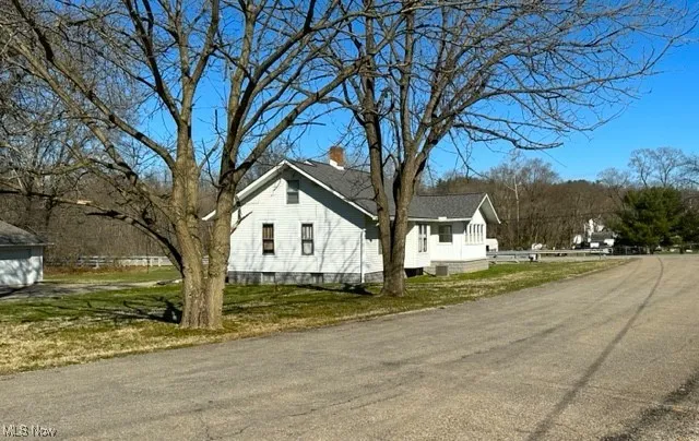 View of property exterior with a yard and a chimney