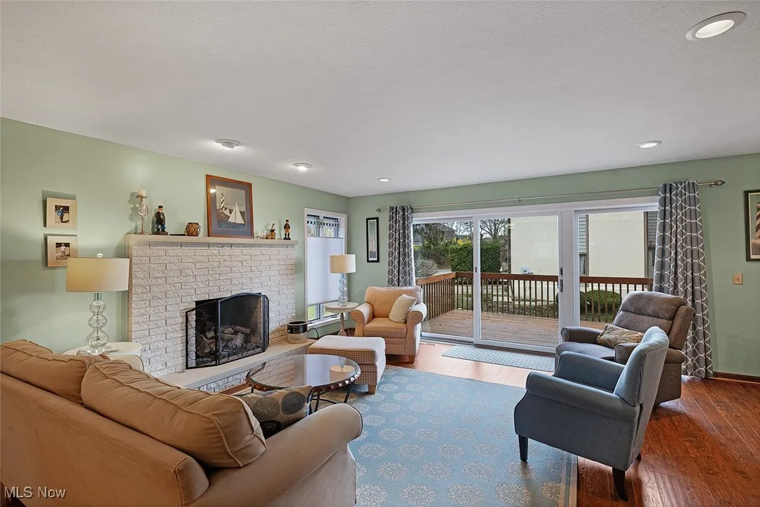 Living area featuring a brick fireplace, recessed lighting, baseboards, and wood finished floors