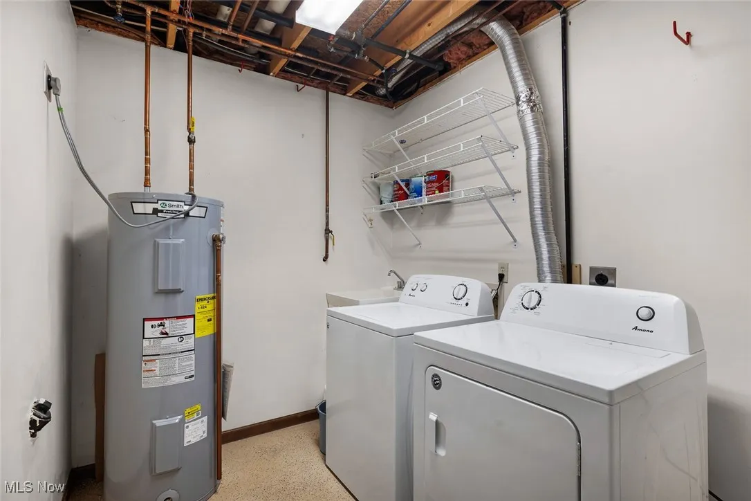 Washroom featuring water heater, washer and clothes dryer, baseboards, and laundry area
