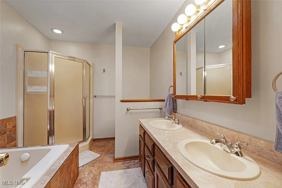 Bathroom with a bath, a sink, and a stall shower