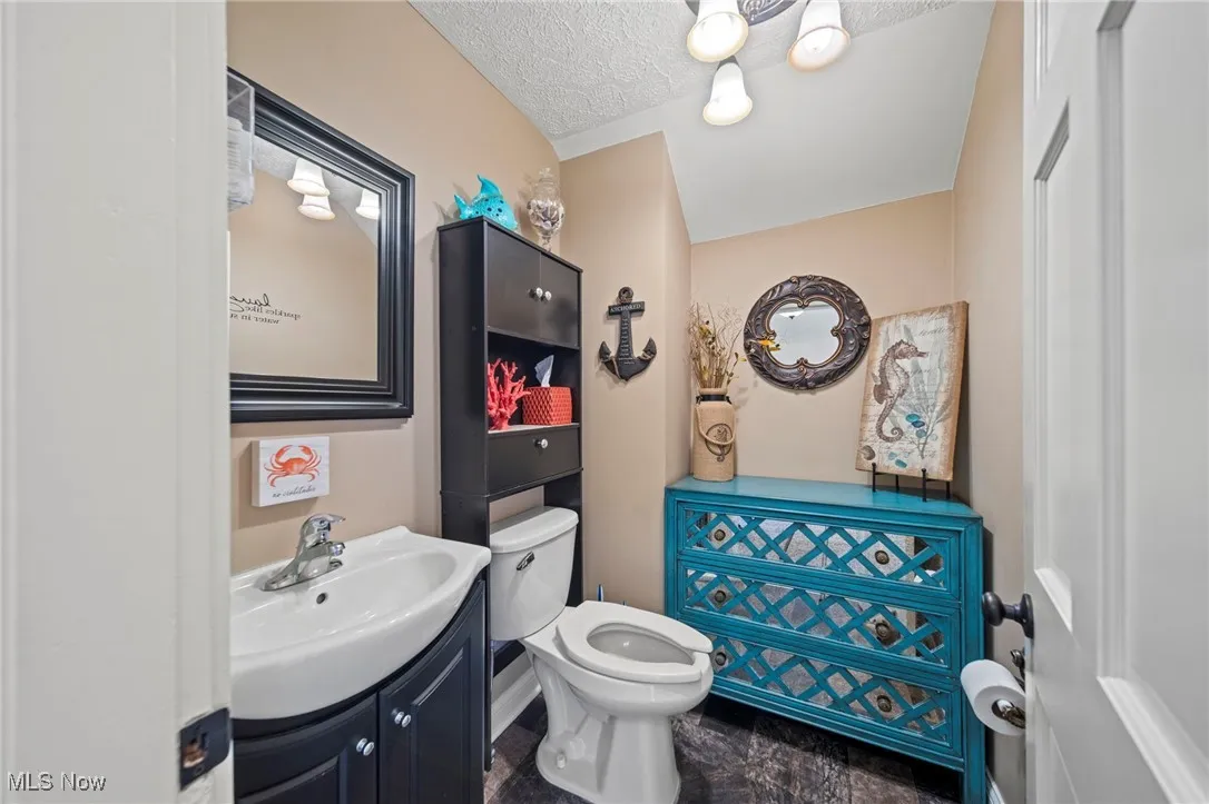 Bathroom with toilet, vanity, and a textured ceiling