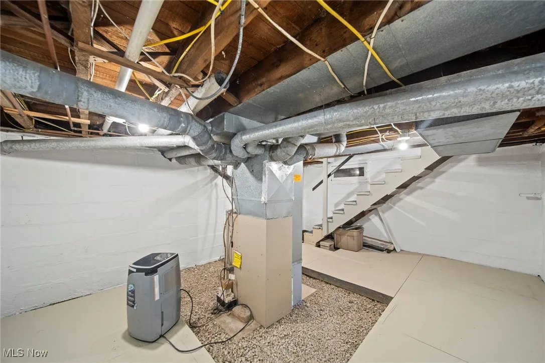 Unfinished below grade area with heating unit and stairway