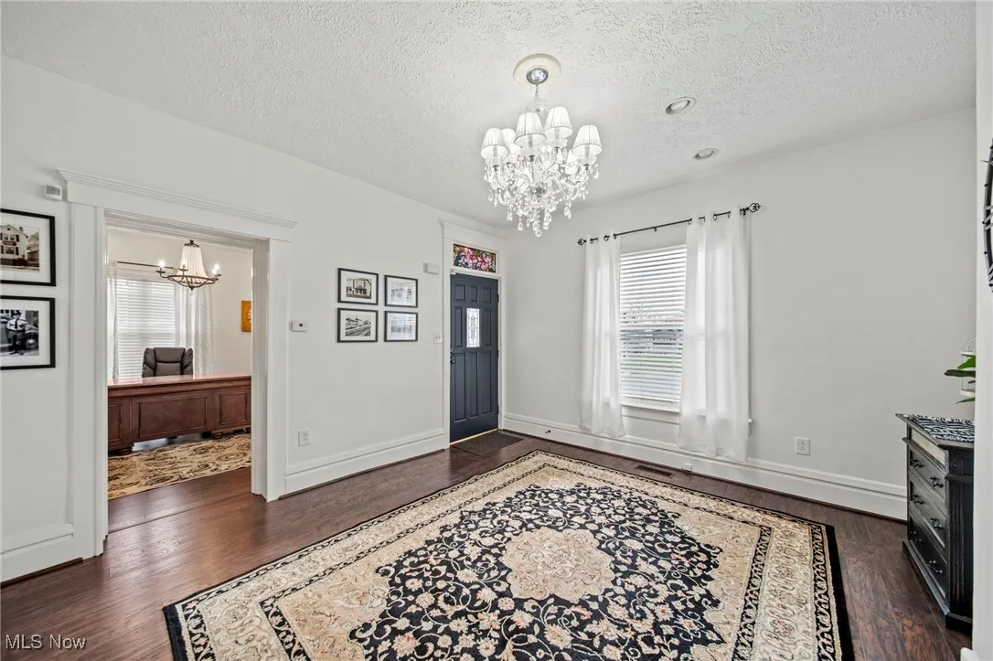 Foyer entrance with a textured ceiling, dark wood-style floors, and a chandelier