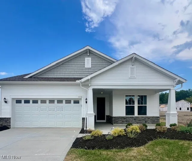 Craftsman house featuring stone siding, a porch, driveway, and an attached garage