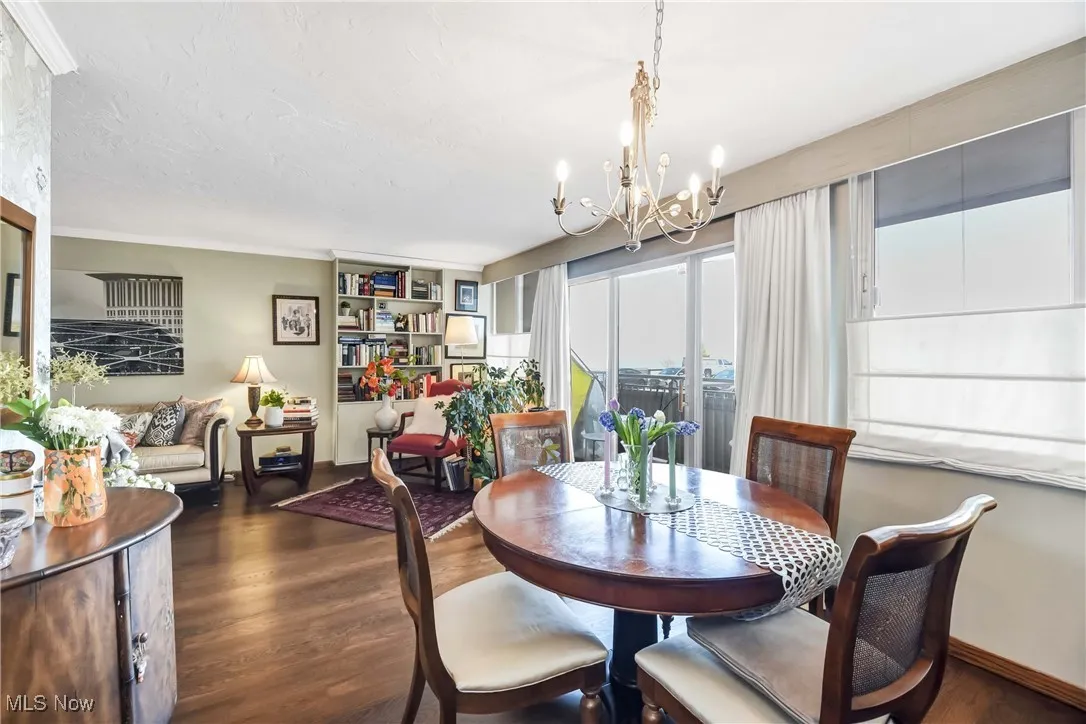 Dining space featuring baseboards, a notable chandelier, wood finished floors, and a textured ceiling