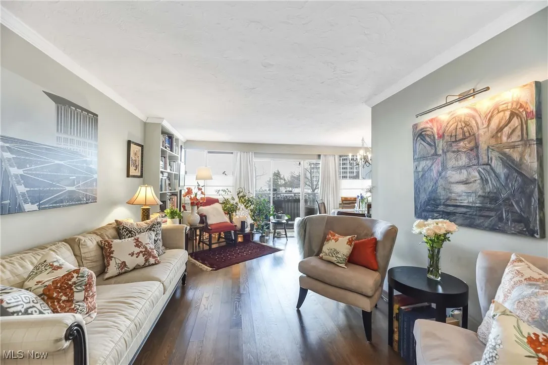 Living room with a notable chandelier, crown molding, hardwood / wood-style flooring, and a textured ceiling