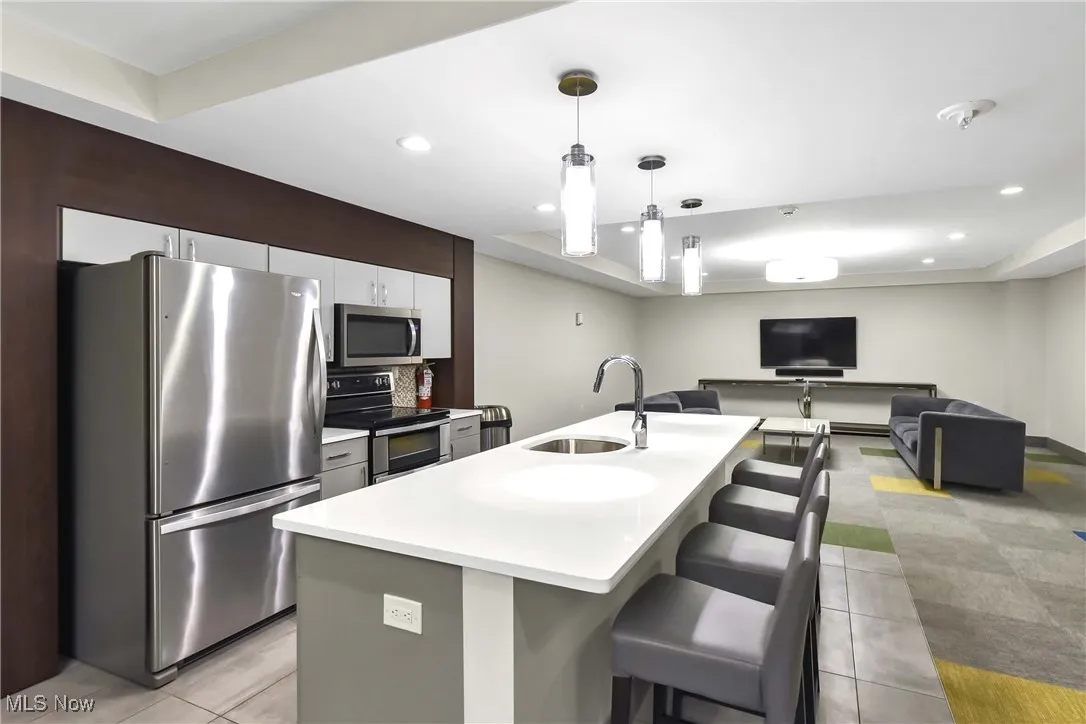Kitchen with light countertops, a kitchen bar, appliances with stainless steel finishes, a sink, and light tile patterned floors