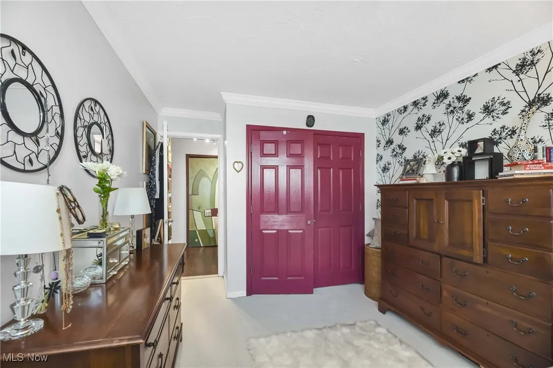 Foyer entrance with baseboards, wallpapered walls, crown molding, and light carpet
