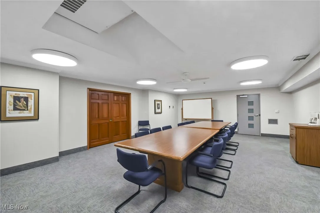 Office with light carpet, baseboards, visible vents, and ceiling fan