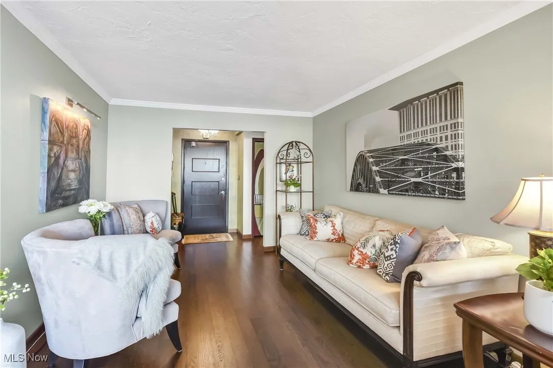 Living room with a textured ceiling, ornamental molding, and wood finished floors
