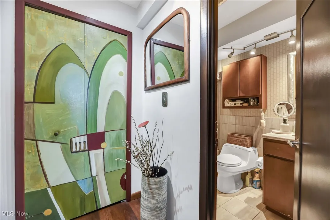 Bathroom with tile walls, rail lighting, toilet, and vanity