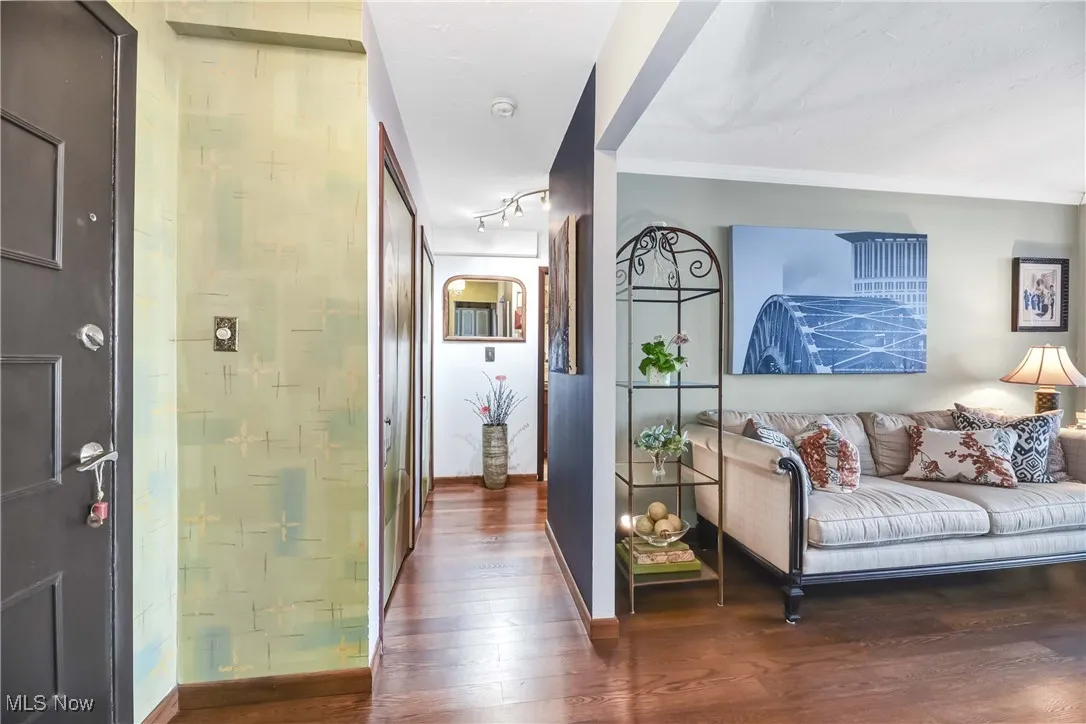 Corridor featuring baseboards, wood finished floors, and track lighting