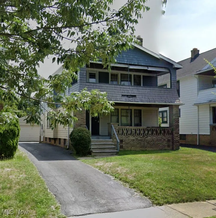 View of front facade featuring an outdoor structure, a balcony, a front yard, and covered porch