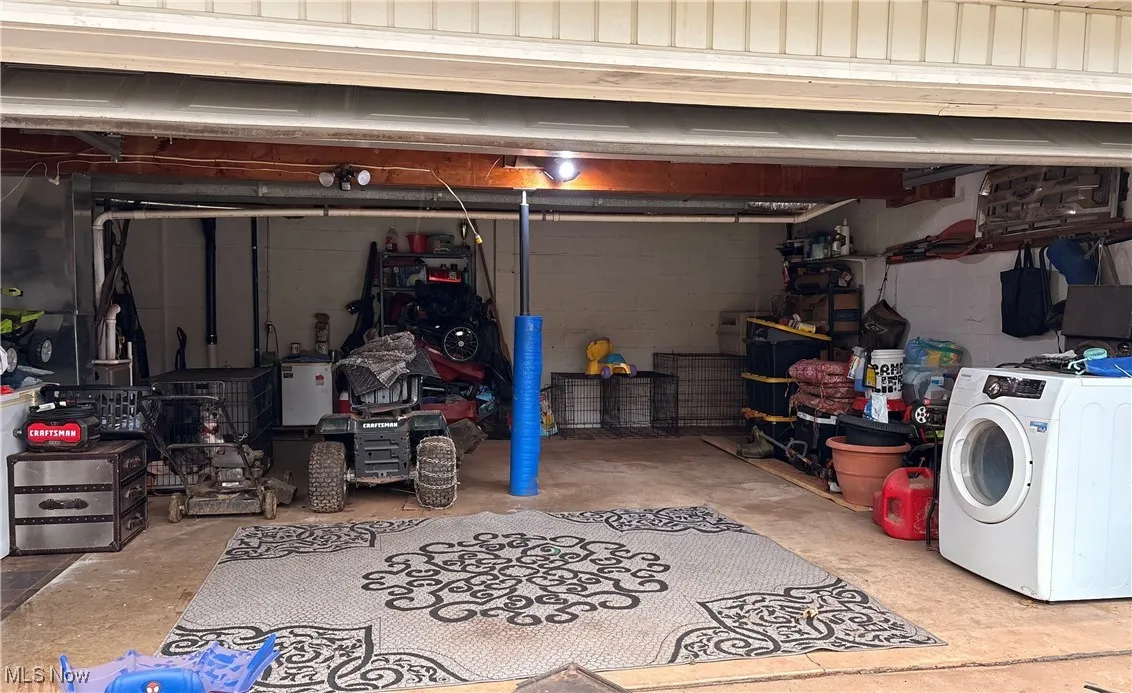 Garage featuring concrete block wall and washer / dryer