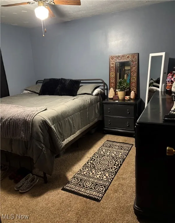 Bedroom featuring carpet flooring, a textured ceiling, and ceiling fan