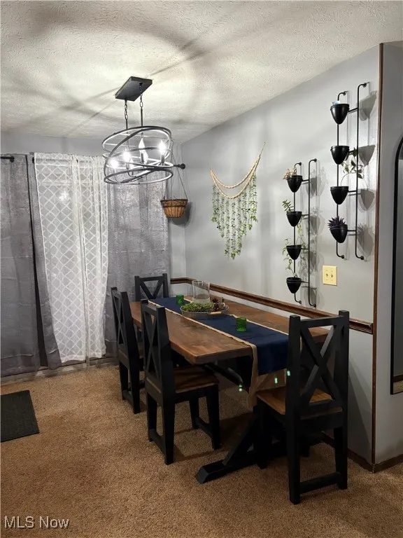 Dining space with a chandelier, carpet floors, and a textured ceiling