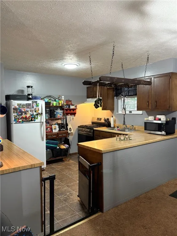 Kitchen with a peninsula, a textured ceiling, and butcher block laminate counters