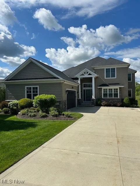 View of front of home featuring driveway, an attached garage, a front lawn, and stone siding