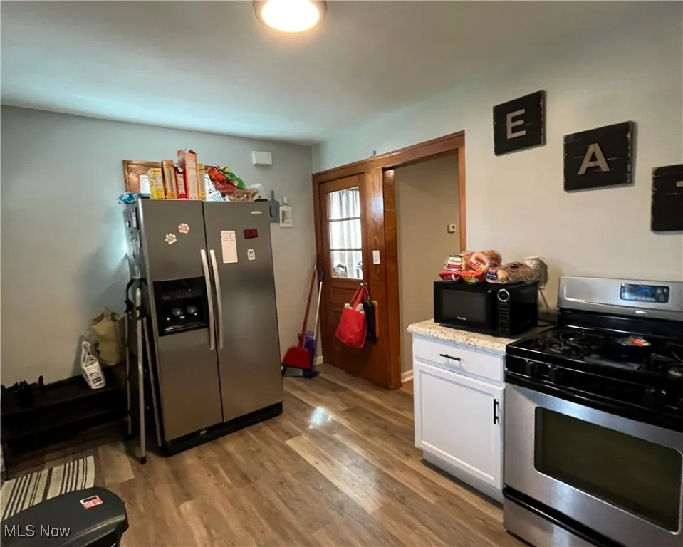 Kitchen featuring light wood finished floors, white cabinetry, and appliances with stainless steel finishes