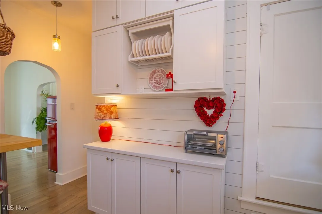 Kitchen with white cabinets, light countertops, arched walkways, and wood finished floors