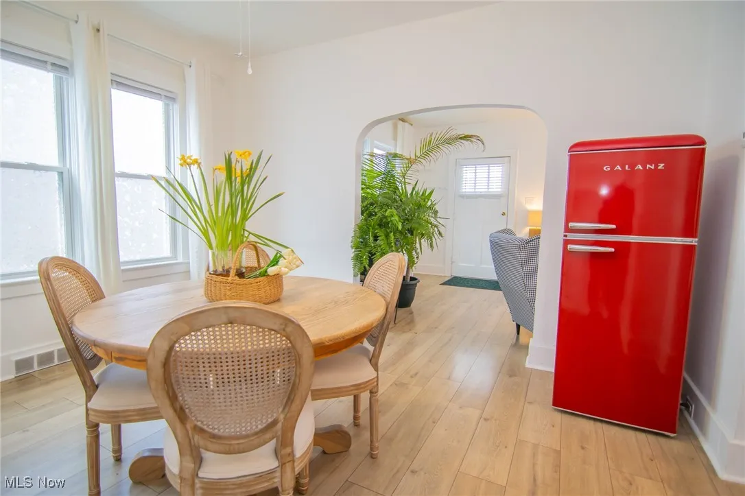 Dining room featuring arched walkways, baseboards, visible vents, and light wood finished floors
