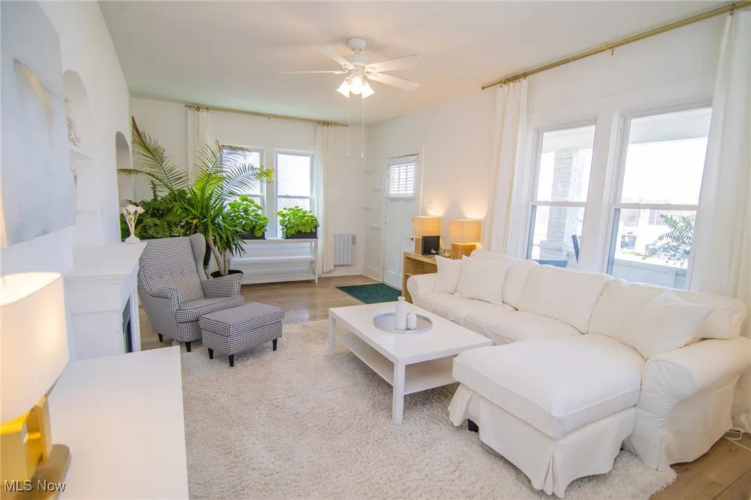 Living room featuring radiator heating unit, a ceiling fan, and wood finished floors