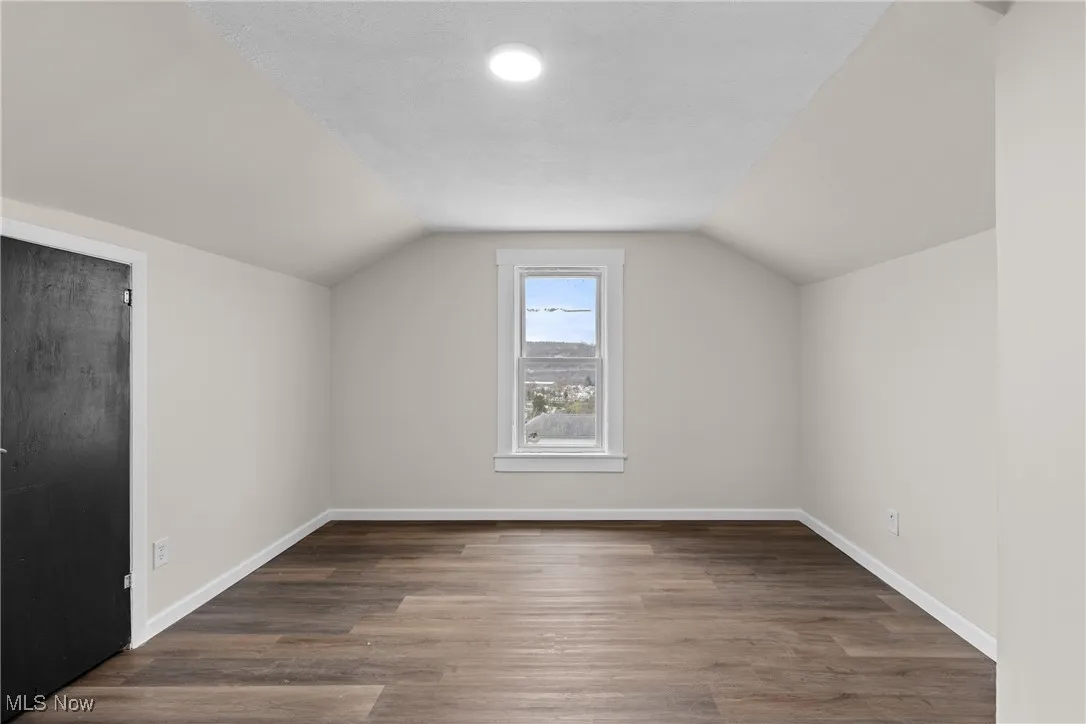 Bonus room featuring baseboards, lofted ceiling, and wood finished floors