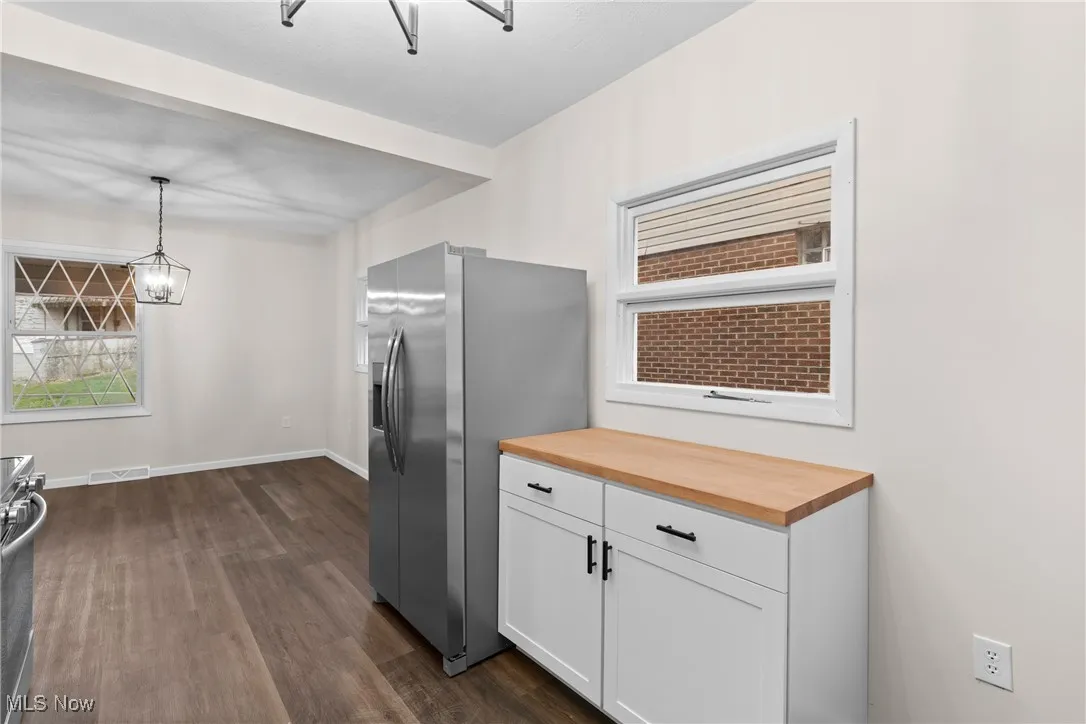 Kitchen featuring butcher block counters, stainless steel appliances, visible vents, white cabinets, and dark wood-style flooring