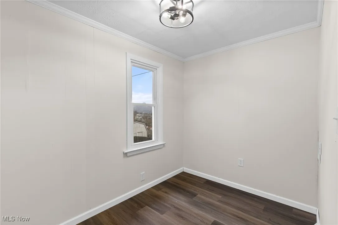 Unfurnished room with baseboards, dark wood-style flooring, and ornamental molding