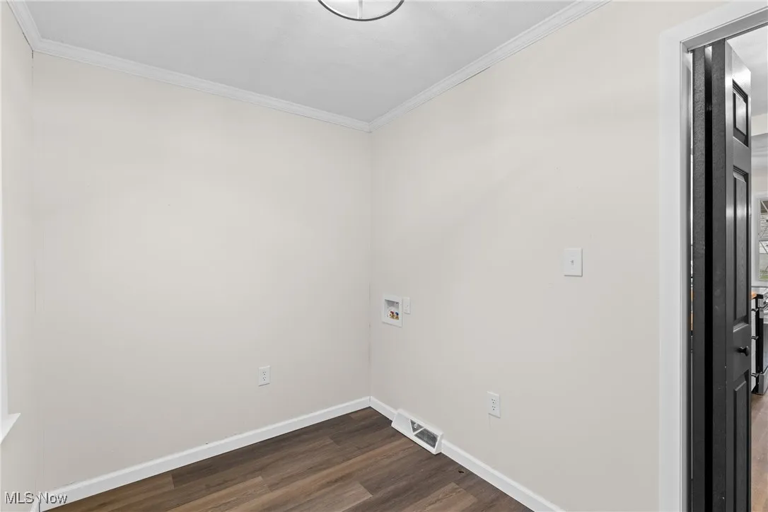 Laundry room featuring crown molding, dark wood finished floors, laundry area, baseboards, and visible vents