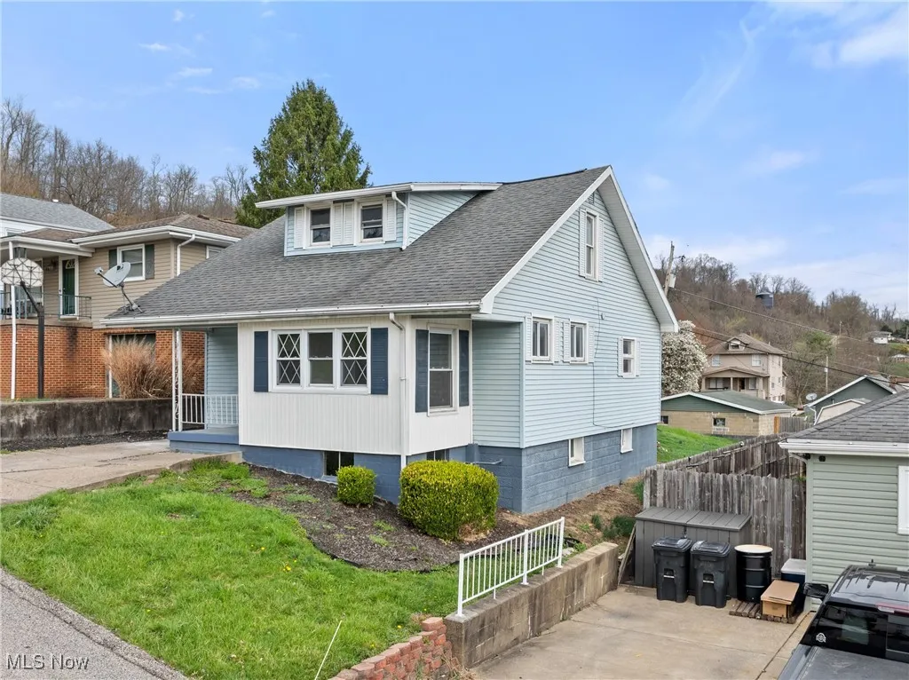 Bungalow-style house with fence, roof with shingles, and a front lawn