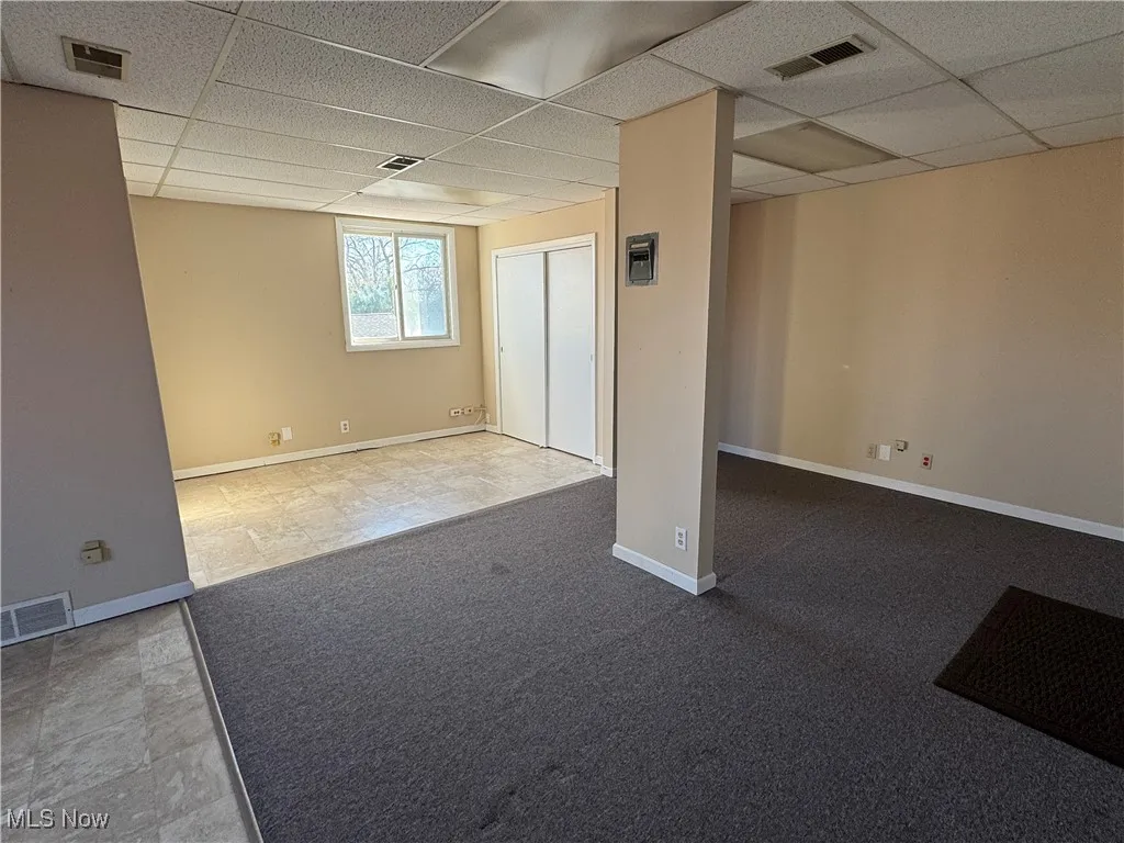 Spare room featuring baseboards, visible vents, and a drop ceiling