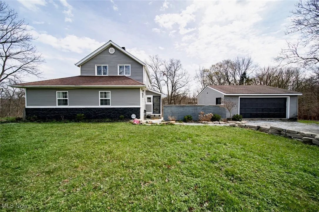 View of front of property with stone siding and a front yard
